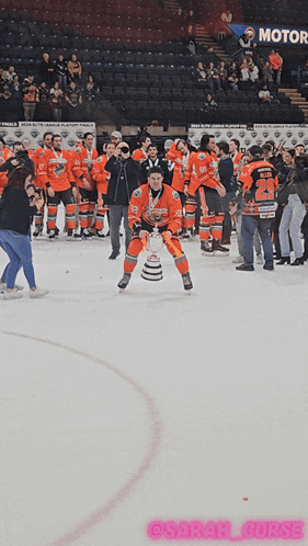 a hockey player holds up a trophy in front of his team