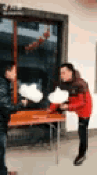 a man and a woman are standing in front of a table .
