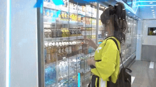 a woman in a yellow shirt is standing in front of a refrigerator .