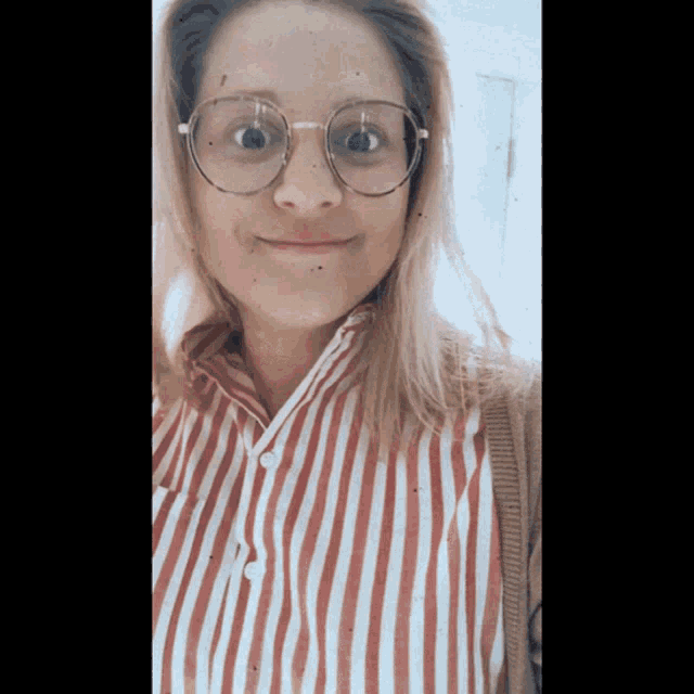 a woman wearing glasses and a striped shirt is smiling