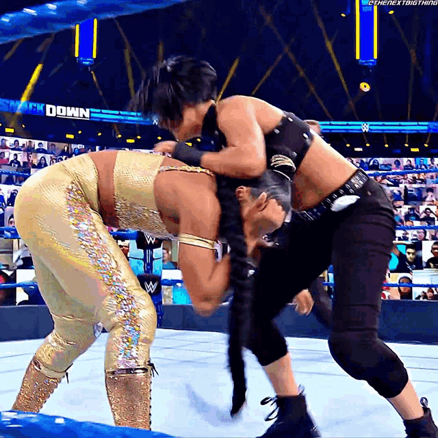 two women are wrestling in front of a sign that says ' shock down '