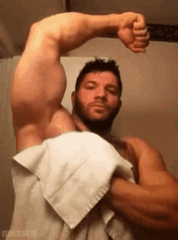 a shirtless man with a beard is wrapped in a white towel .