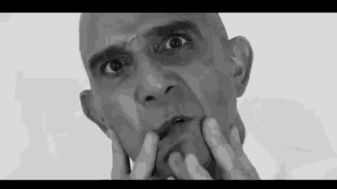a black and white photo of a man holding his face .