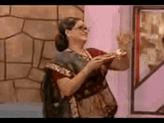 a woman in a sari is standing in front of a mirror holding a plate .