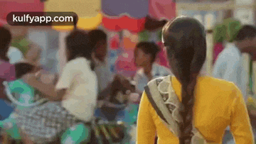 a woman in a yellow shirt is walking through a crowded street .