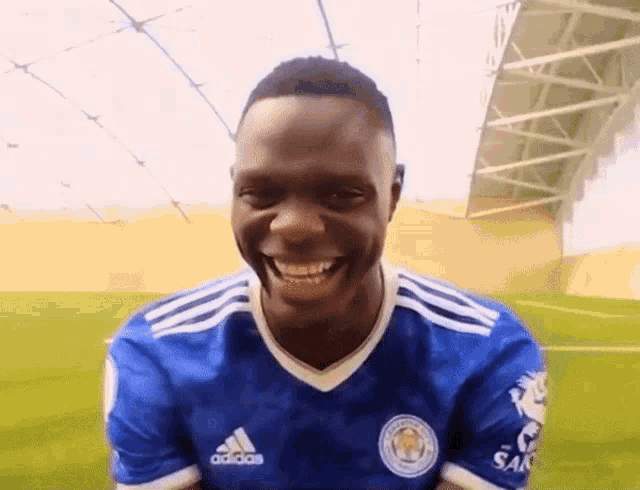 a man in a blue adidas shirt is smiling