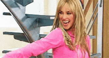a woman in a pink shirt is standing next to a set of stairs .