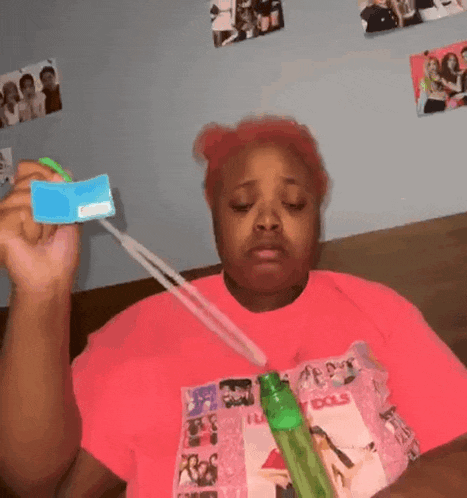 a woman in a pink shirt with the word dolls on it is blowing soap bubbles