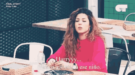 a woman in a red sweater sits at a table and says harryyy vamos a matar ese niño