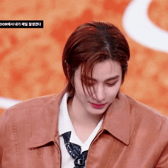 a woman wearing a brown jacket and tie looks down at something