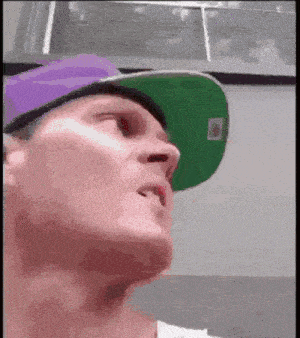 a man wearing a green hat and a purple hat is looking up
