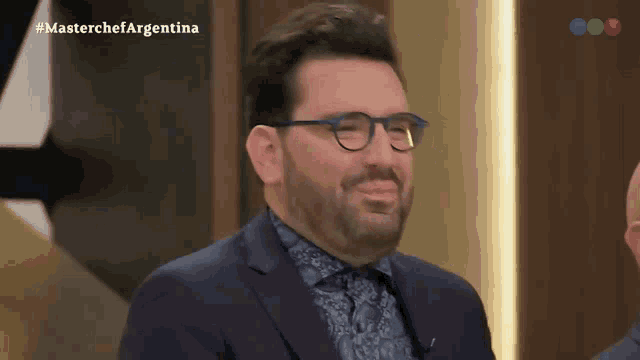 a man wearing glasses and a suit is appearing on a television show called masterchef argentina
