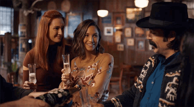 a group of people toasting with a man wearing a sweater that says ' cowboy '