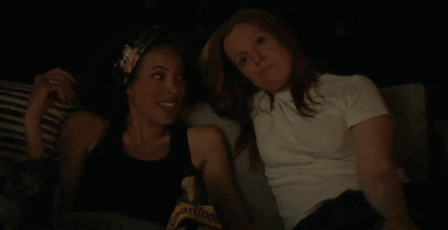 two women are sitting on a couch and one of them is wearing a t-shirt that says hartford