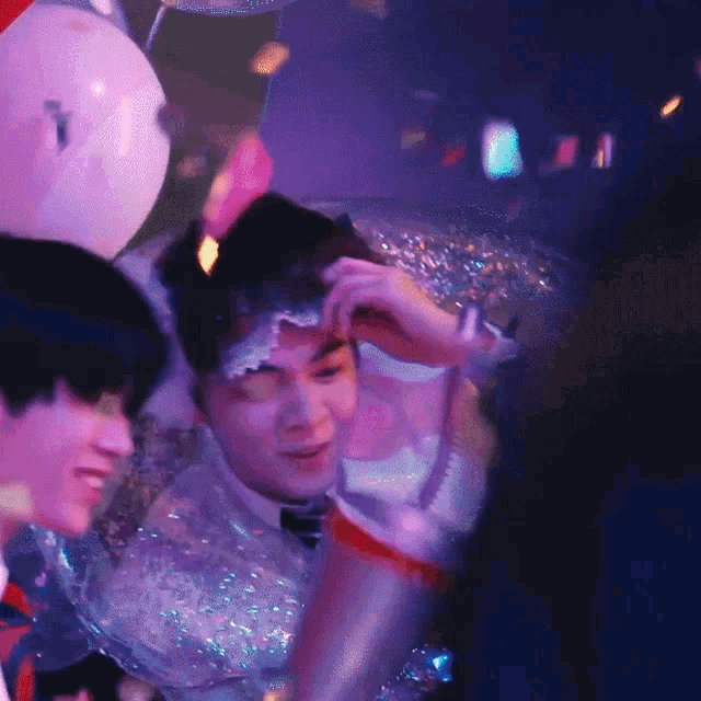 a group of people are gathered in a room with pink balloons