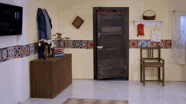 a corner of a room with a door and a dresser with a vase of flowers on it