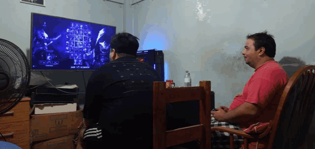 two men are playing a video game on a flat screen television