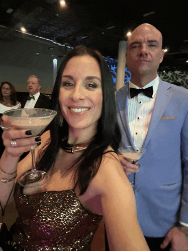 a woman holding a martini glass next to a man in a suit