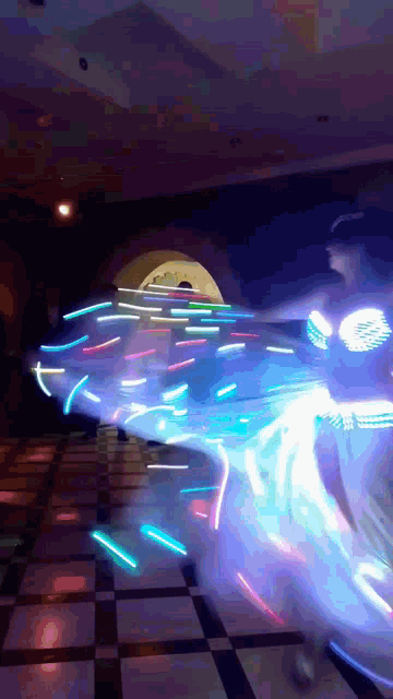 a woman is dancing with glowing lights on her arms
