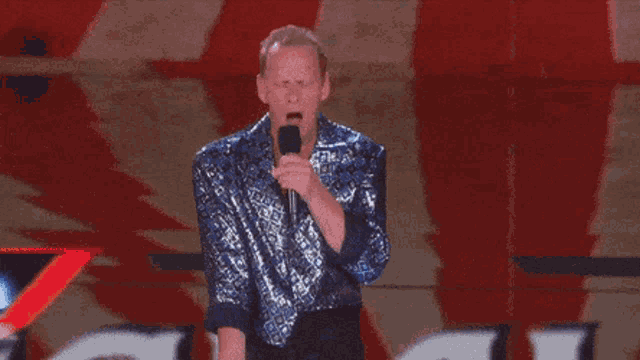 a man in a blue shirt is holding a microphone in his mouth