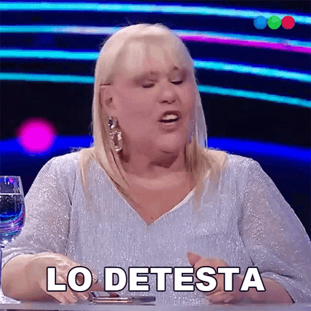 a woman sitting at a table with the words lo detesta written on the bottom