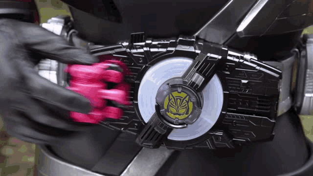 a person is wearing a black glove and holding a pink object in their hand