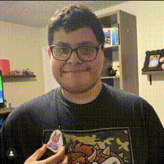 a man wearing glasses and a sonic the hedgehog t-shirt is holding a sticker .