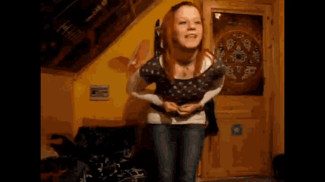 a woman is dancing in a room with a yellow wall and a green circle on the door