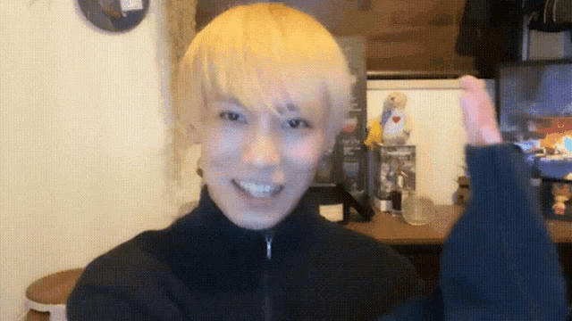 a man with blonde hair is smiling and giving the thumbs up