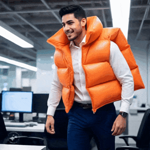 a man wearing a large orange vest is walking in an office