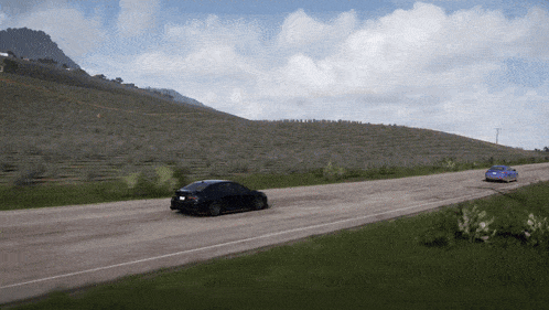 two cars are driving down a road with a mountain in the background