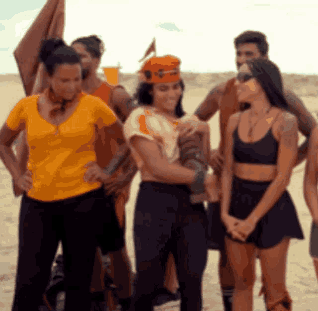 a group of people are standing on a beach and one of them is wearing a red hat
