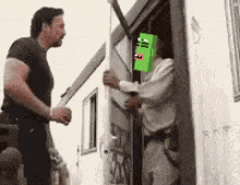 a man is holding a sword while another man holds a green box on his head .