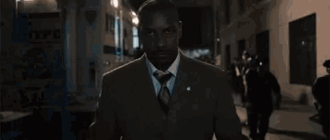 a man in a suit and tie is walking down a city street at night .