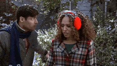 a man and a woman wearing ear muffs are standing in the snow