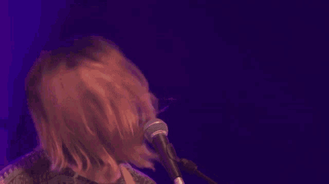 a man with long hair is singing into a microphone