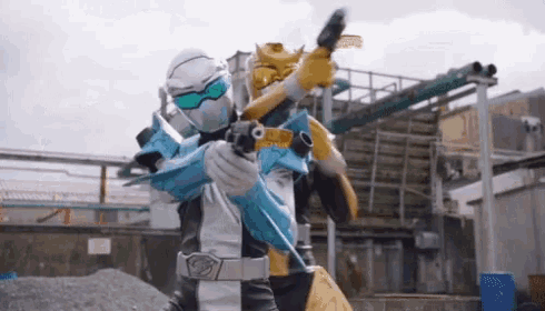 a man in a superhero costume is holding a gun while standing next to another man .