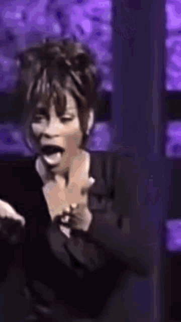 a woman in a black jacket is laughing with her mouth open