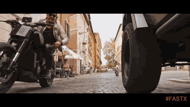 a man is riding a motorcycle down a cobblestone street with #fastx written on the bottom