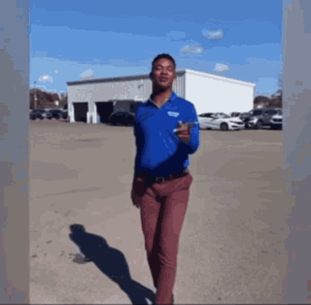 a man in a blue shirt and red pants is pointing at something