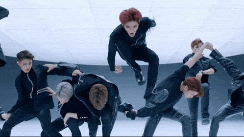 a group of men are dancing in a room with a white ceiling