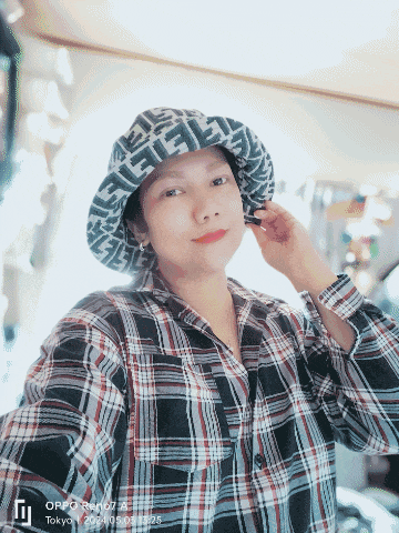 a woman wearing a plaid shirt and a fendi hat taking a selfie