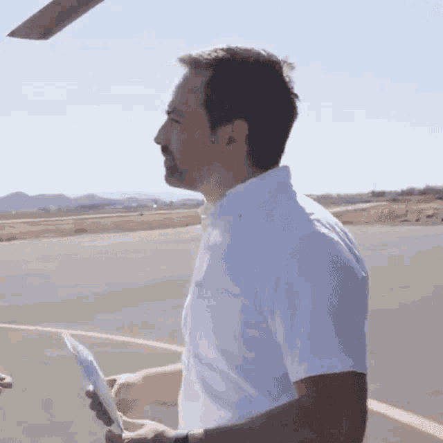 a man in a white shirt holds a piece of paper in his hand