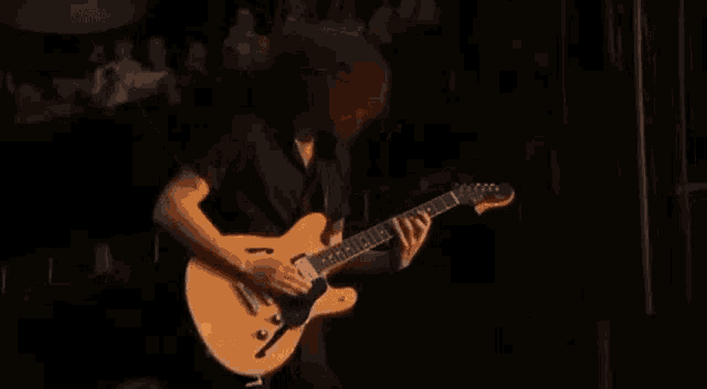 a man with long hair is playing a guitar