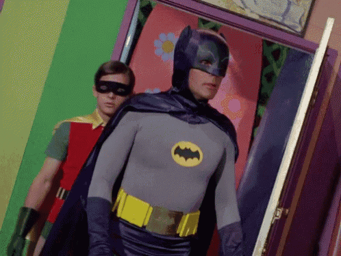 a man in a batman costume is standing next to a man in a red shirt