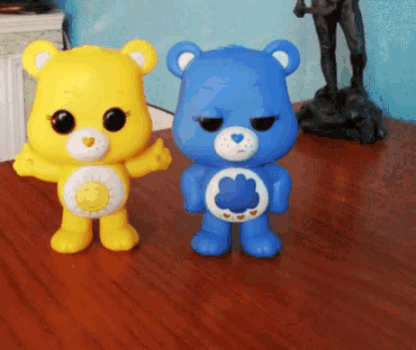 a yellow care bear and a blue care bear are sitting on a table
