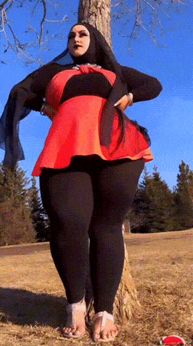 a woman in a hijab is standing next to a tree in a field