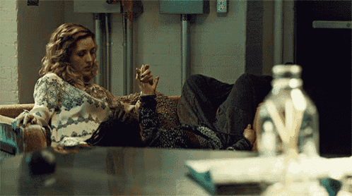 a woman sits on a couch holding a man 's hand