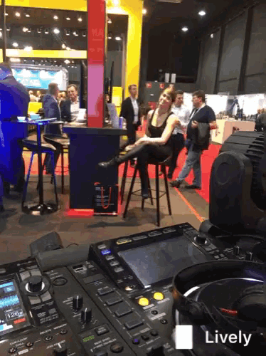 a woman sits on a stool in front of a pioneer dj mixer