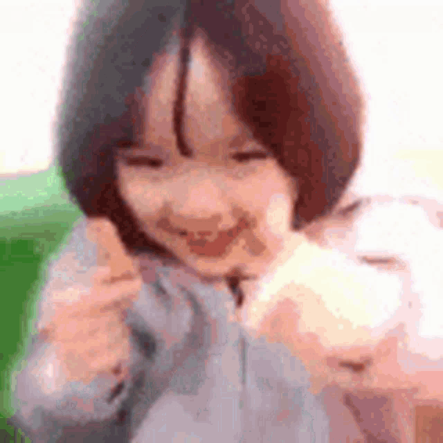 a little girl with short hair is smiling and holding a white object in her hands .